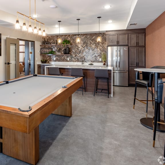 a pool table in a clubhouse with a kitchen and a bar