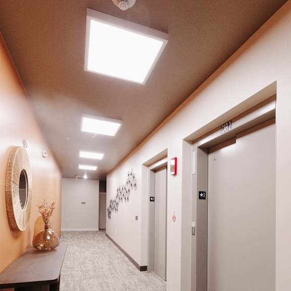 a hallway with white walls and white doors and a table with a vase