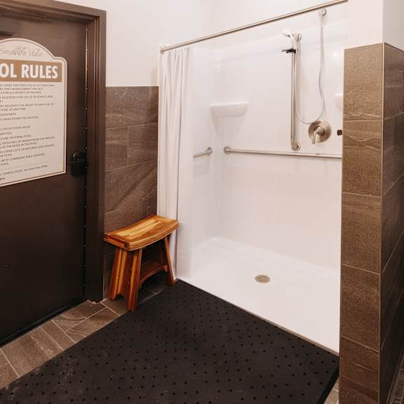 a small bathroom with a shower and a wooden stool