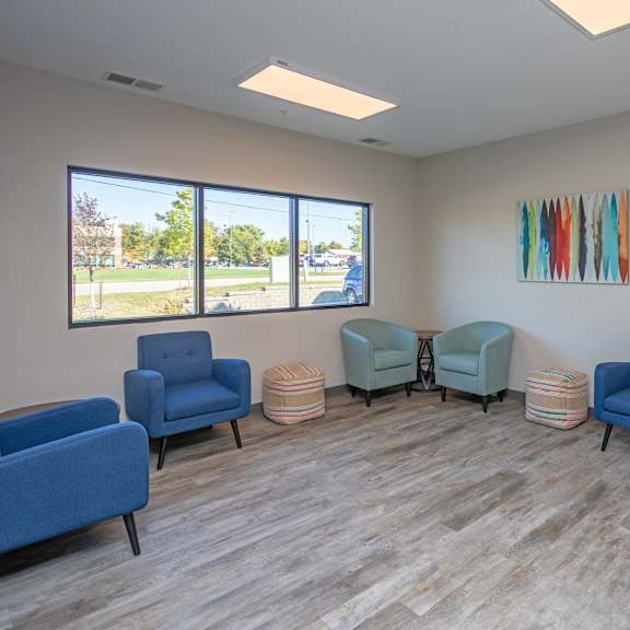 a room with blue chairs and a painting on the wall.