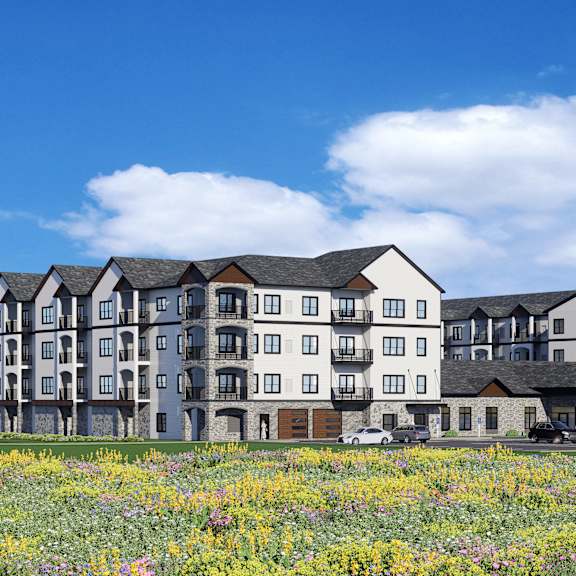 a large, modern apartment building with a grassy field in front.
