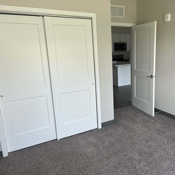 a bedroom with two closets and a door to a kitchen
