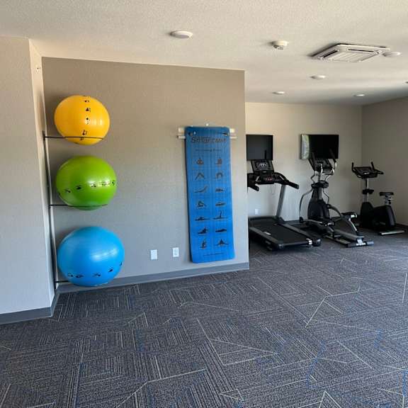 a gym with weights and balls in a room with windows