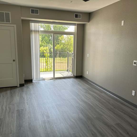 an empty living room with a door to a balcony