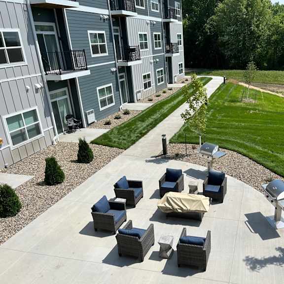 an outdoor area with couches and tables in front of an apartment building