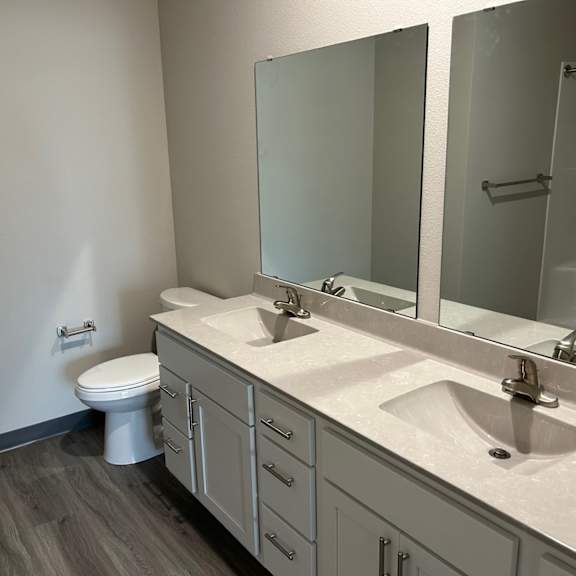 a bathroom with two sinks and a toilet and two mirrors