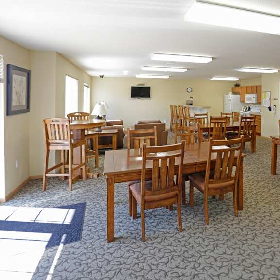 a room with a carpeted floor and wooden chairs and tables.