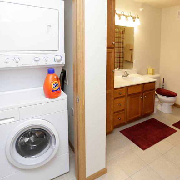 a white washing machine is in a small bathroom with a towel hanging on the wall.