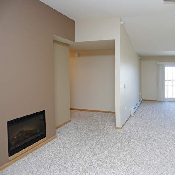 a spacious living room with a fireplace and a ceiling fan.