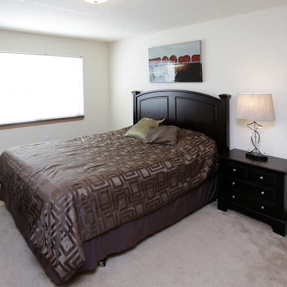 a bedroom with a large bed and a nightstand with a lamp.