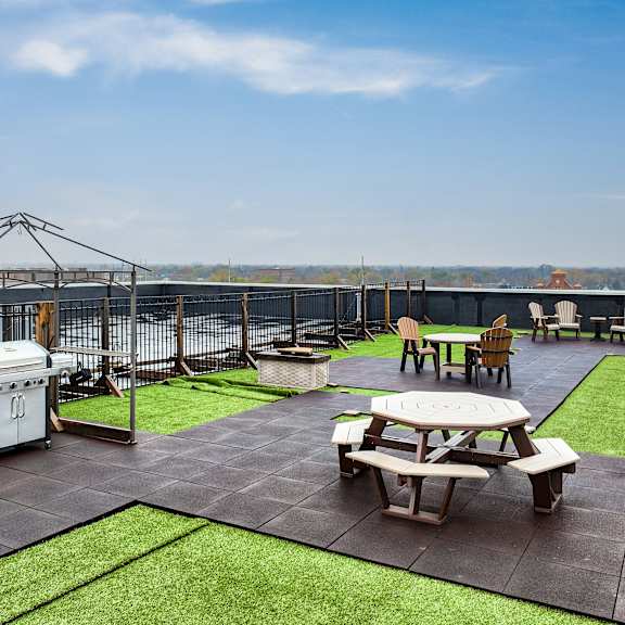 a rooftop patio with tables and chairs and a grill