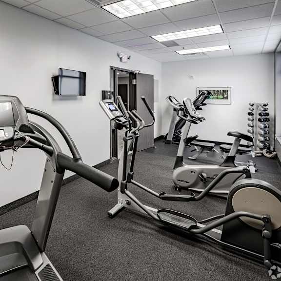 a gym with various exercise machines and a tv