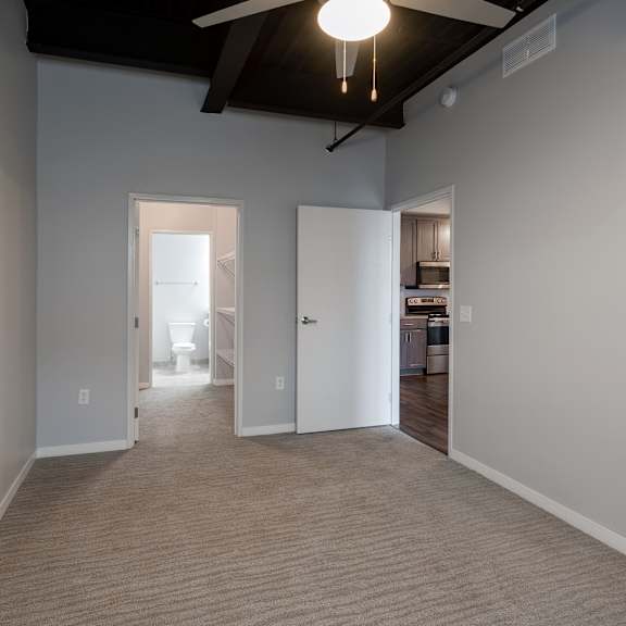 an empty living room with a carpet and a ceiling fan
