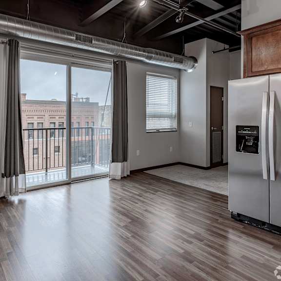 an empty living room with a large window and a door to a balcony