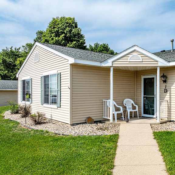 a beige house with a white door and a small porch.