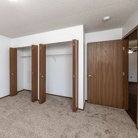 a room with a carpeted floor and three open doors.