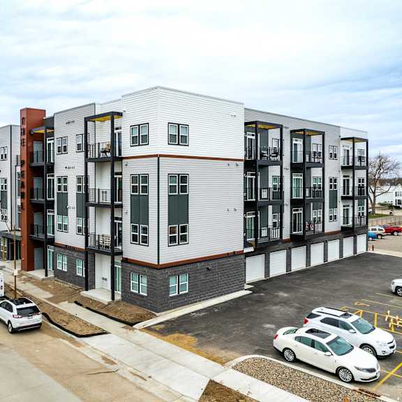 a parking lot with cars and a building with many windows.