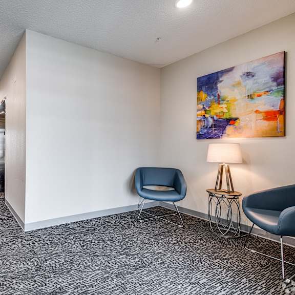 a hallway with a blue chair and a painting on the wall.