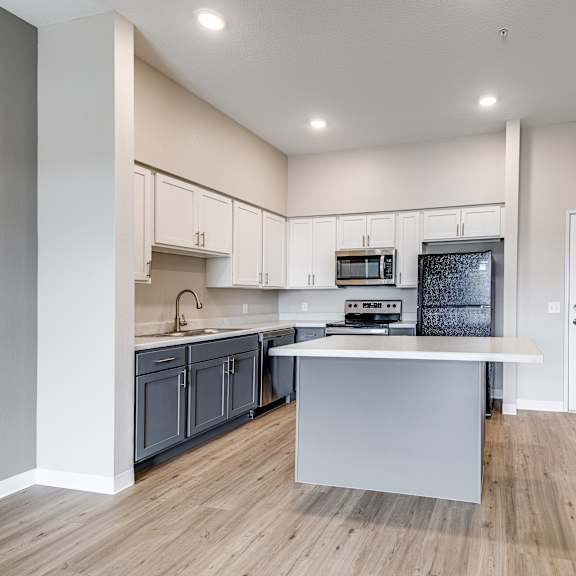 a kitchen with a white island and wooden floors.