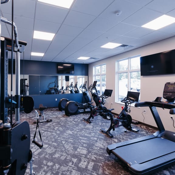 a gym with various exercise machines and a tv