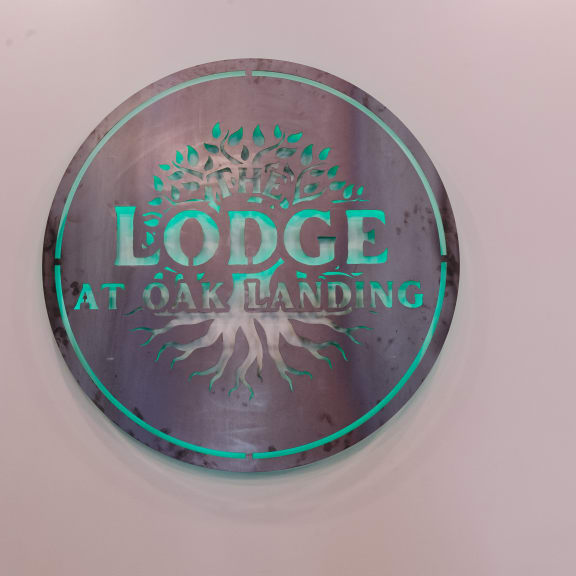 a metal button with a tree and the words lodges at oak landing on it