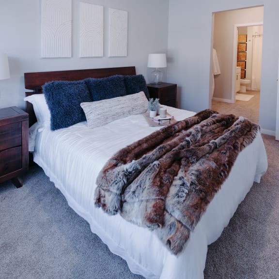 a bedroom with a white bed and a furry blanket