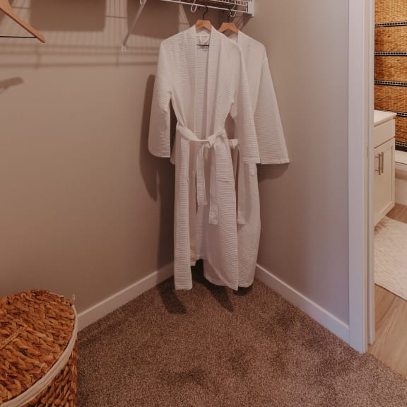 a white robe hangs on a rack in a closet