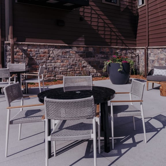 a patio with a table and chairs and a fire pit