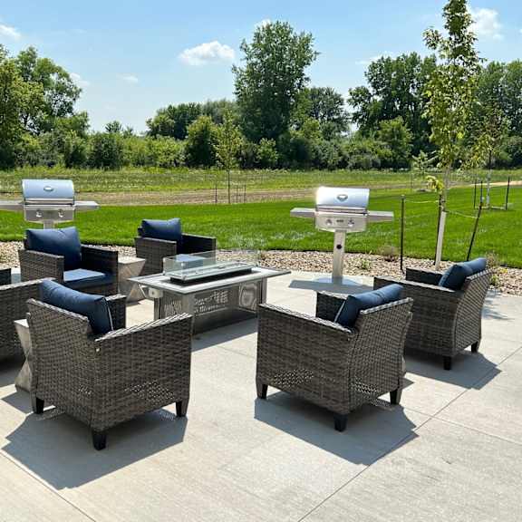 a patio with chairs and a table and a grill