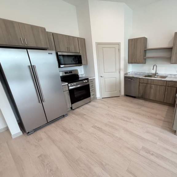 a kitchen with a refrigerator, oven, and microwave.