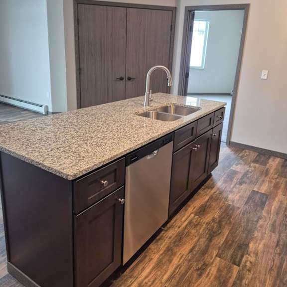 a kitchen with a granite countertop and dark wood cabinets.