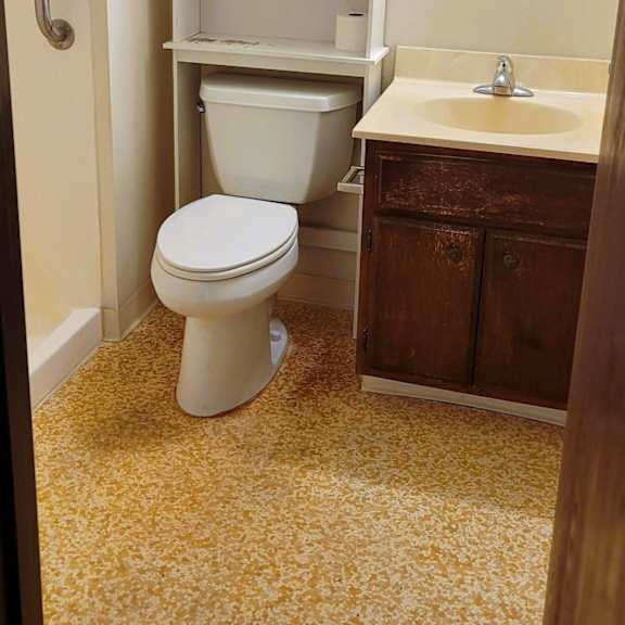 a white toilet sits in a bathroom with a sink and medicine cabinet.