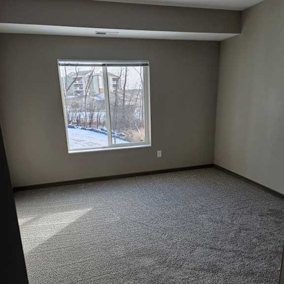 a room with a carpeted floor and a window showing a snowy scene outside.