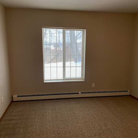 a window with blinds in a room with a light on the wall.