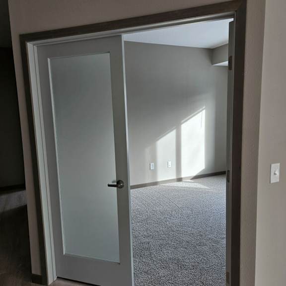 a white door is open to a room with a carpet.