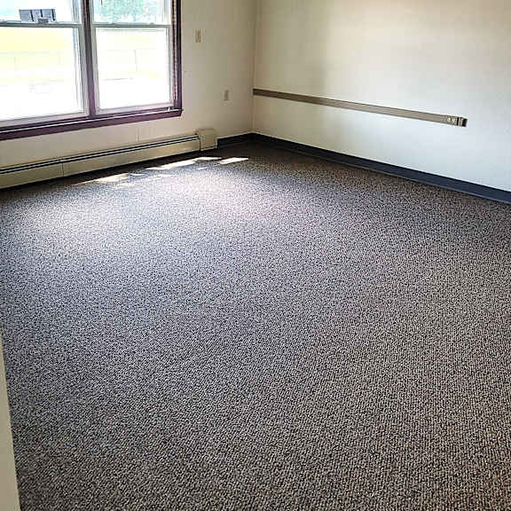a room with a carpeted floor and a window with blinds.