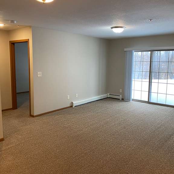 a room with carpeted floor, a door, and a window with blinds.