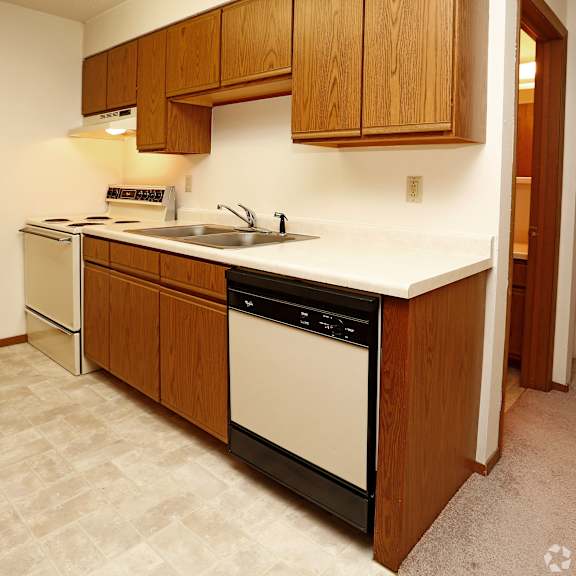 a kitchen with a white counter top and wooden cabinets.