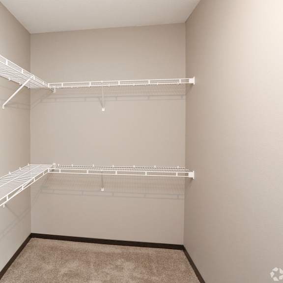 a spacious closet with white shelves and a white wall