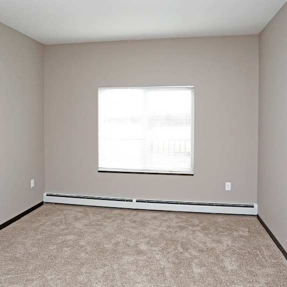 an empty room with a window and carpet