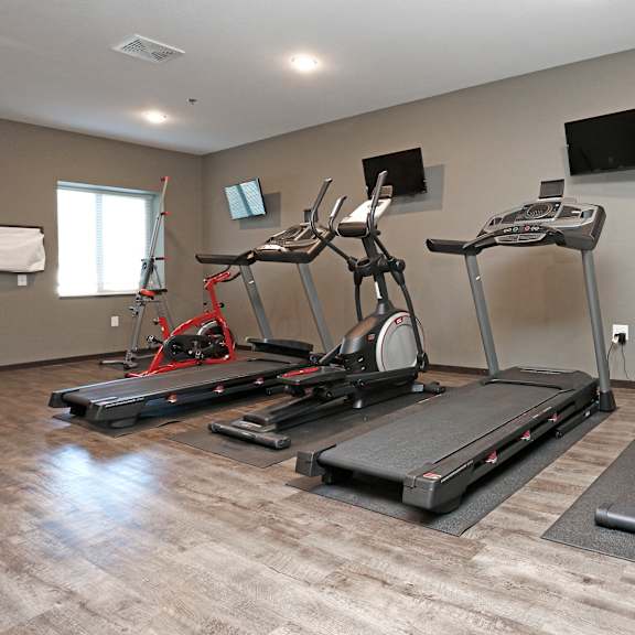 a gym with treadmills and other exercise equipment on a wooden floor