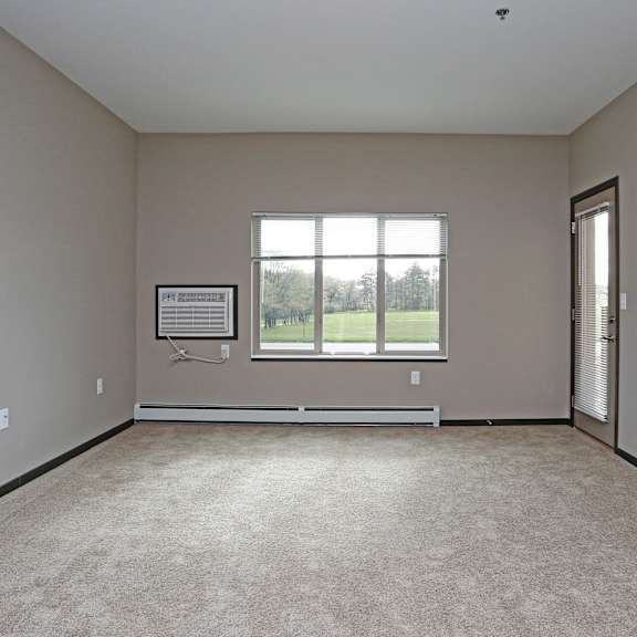 an empty living room with a window and carpet