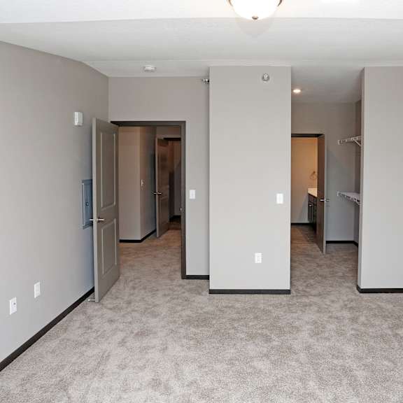 a bedroom with a carpeted floor and several closets and mirrors
