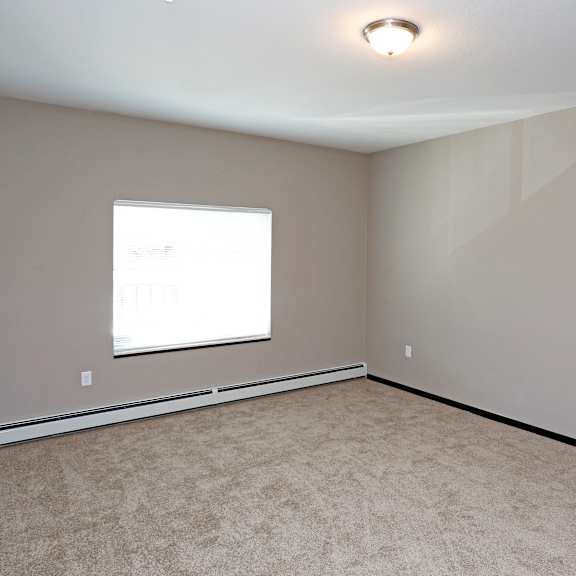 an empty room with a window and carpet