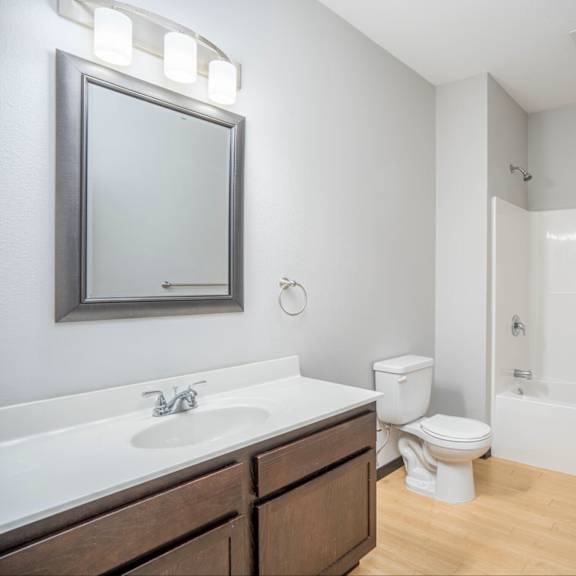 a white bathroom with a toilet, sink, and mirror.
