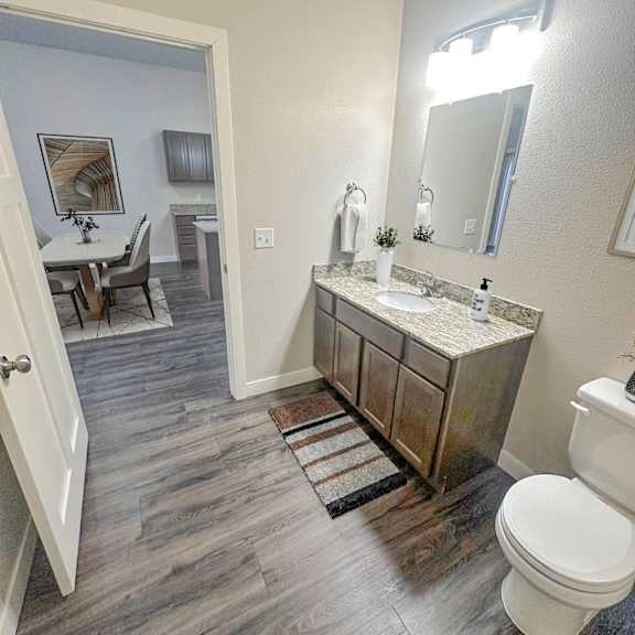 a bathroom with a white toilet, sink, and mirror.