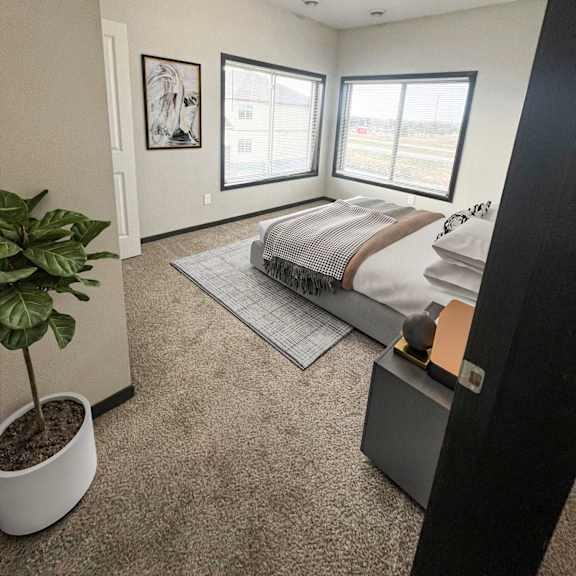 a bedroom with a bed, a plant, and two pictures on the wall.