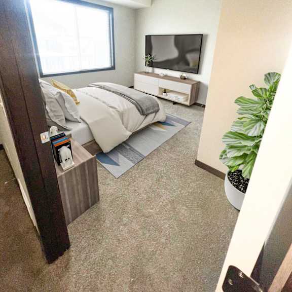 a bedroom with a bed, nightstand, and a tv on the wall.