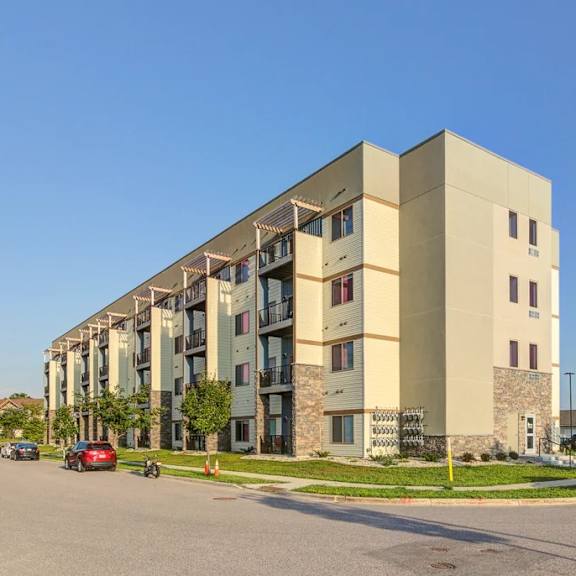 a large apartment building with cars parked in front.