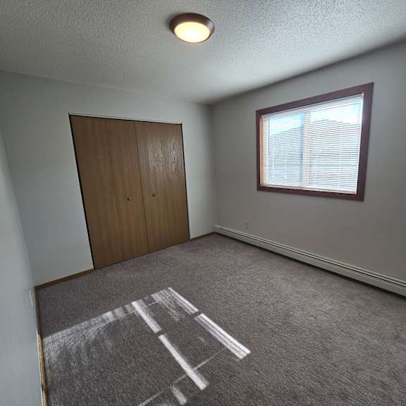 a room with a brown door and a window with blinds.